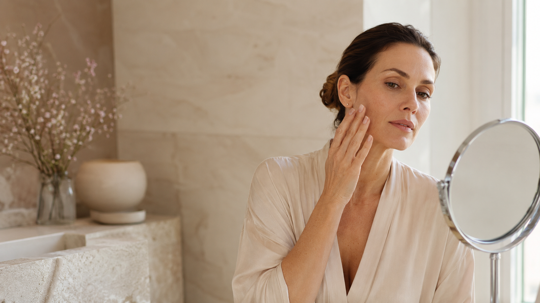 Adult woman examining her skin in a mirror before choosing an at-home EMS facial device