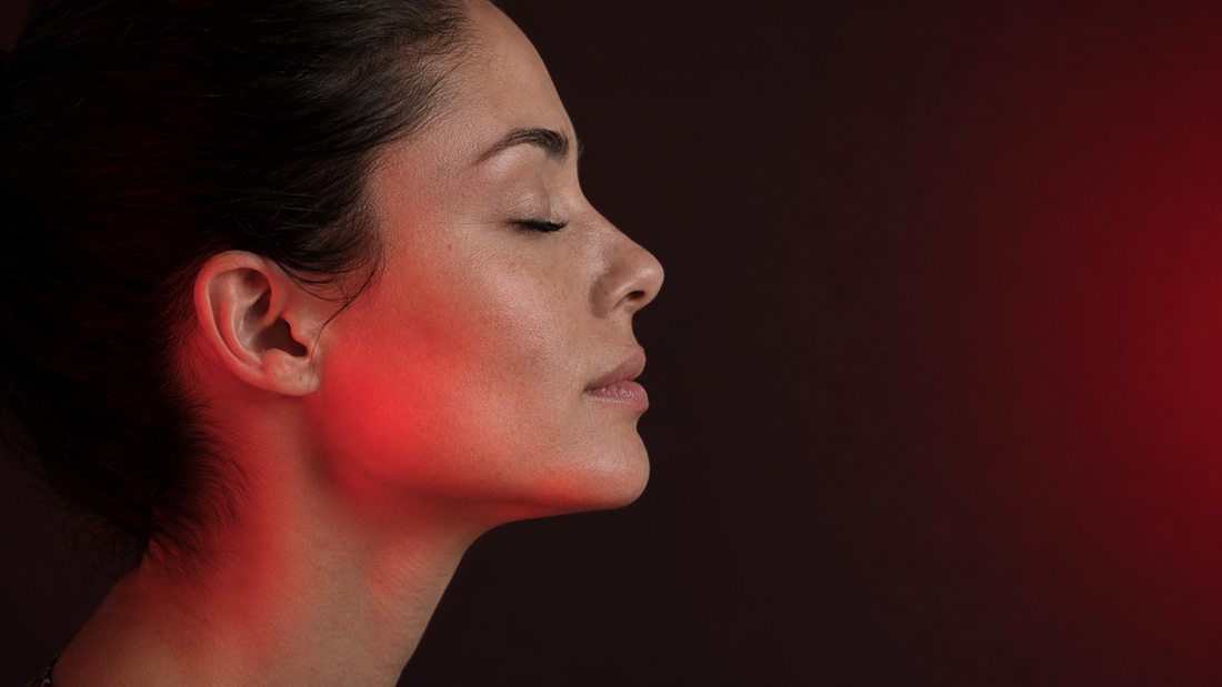 Side-profile portrait in soft red light illustrating facial device technologies